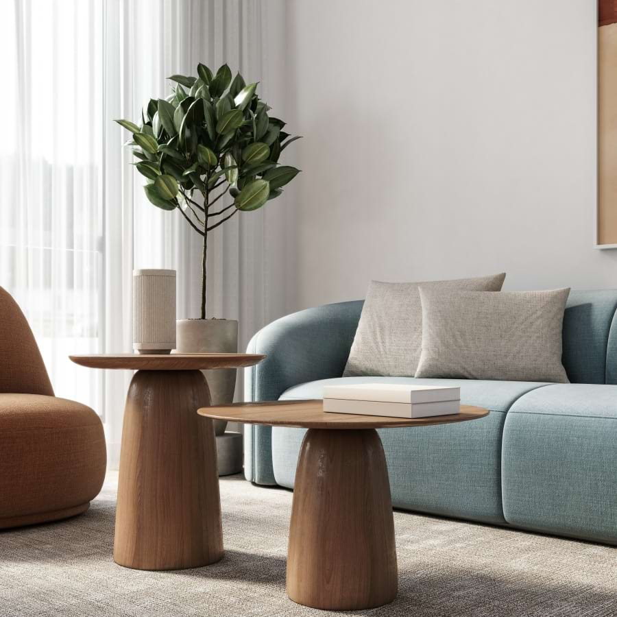 Modern living room with light blue curved sofa, rust orange bouclé accent chair, and two round wood pedestal side tables on a woven area rug